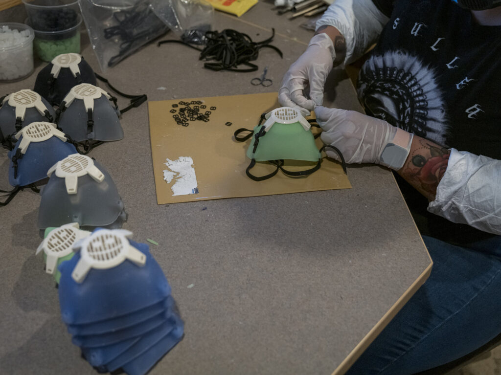 Earlier this year, Monster City Studios, a company that normally makes amusement park and movie props, pivoted to manufacturing MCS face shields with forehead protection. It was one of many small companies to make the switch. A worker wearing protective gloves attaches an elastic strap to a silicone face mask at Mask & Shield, a division of Monster City Studios, in Fresno, California, U.S., on Wednesday, May 27, 2020. Monster City Studios, a company that normally makes amusement park and movie props, has pivoted to manufacturing MCS face shields with forehead protection. Photographer: David Paul Morris/Bloomberg via Getty Images