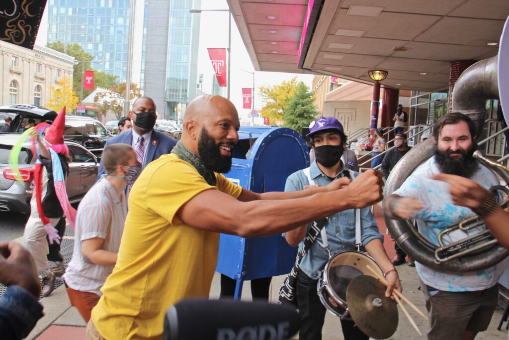 2020 10 23-e lee-common the rapper-philadelphia liacouras center-cirque d’vote 1 Common, the rapper also known as Lonnie Rashid Lynn, bumps fists with members of the Snack Time Band outside the Liacouras Center after an impromptu jam session. (Emma Lee/WHYY)