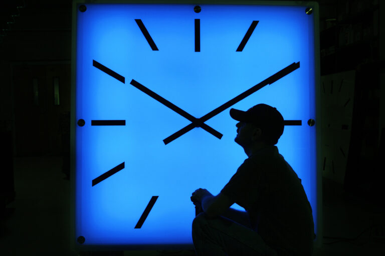In this Oct. 30, 2008, file photo, Electric Time Company employee Dan Lamoore adjusts the color on a 67-inch square LED color-changing clock at the plant in Medfield, Mass. (AP Photo/Elise Amendola)