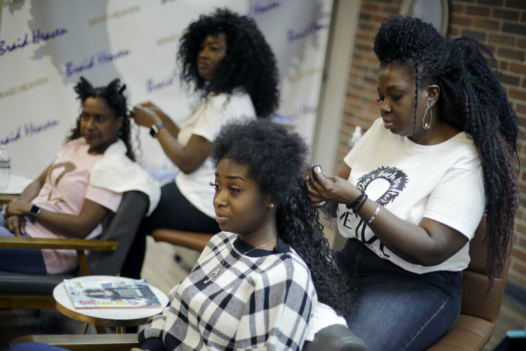 Hairstyles Bias Legislation Sisters Shelly Smith, back, and Glynnis Smith, right, braid hair for Bridget Dunmore, left, and Alicia McGee, front at their salon, Braid Heaven, Tuesday, Jan. 28, 2020 in Kansas City, Kan. Legislators are considering whether to revise their states' anti-discrimination laws to ban bias in housing, employment and public accommodations based on hairstyles. (AP Photo/Charlie Riedel)