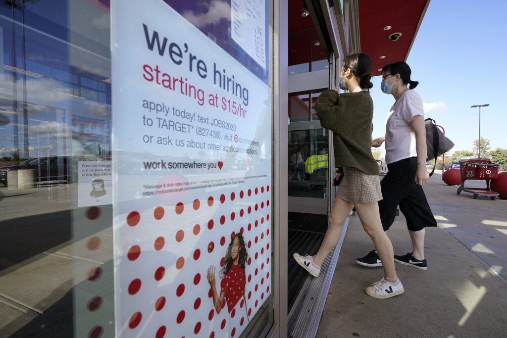 Passers-by walk past a hiring sign as they enter a Target retail store location, Wednesday, Sept. 30, 2020, in Westwood, Mass. (AP Photo/Steven Senne)