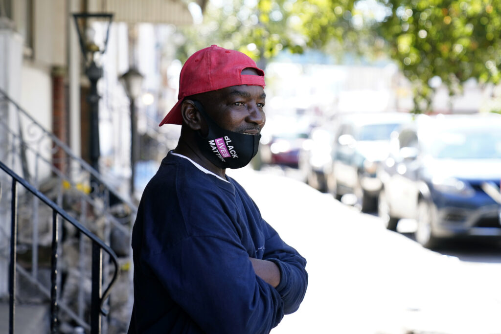Black man standing on West Philadelphia face mask donning a face mask