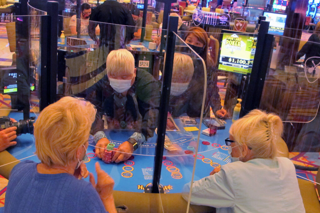 Virus Outbreak-State of Casinos See-through barriers separate gamblers and a dealer at a card table at the Hard Rock casino