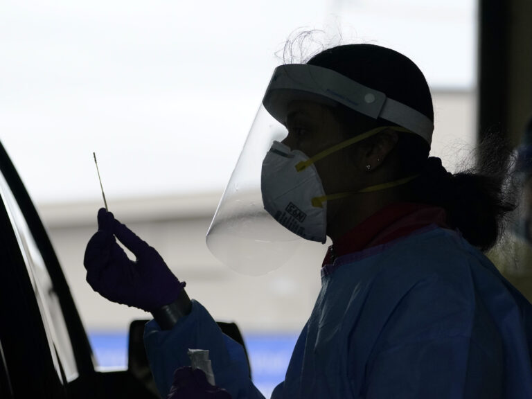 A University of Washington research coordinator holds up a swab after testing a someone for coronavirus on Oct. 23 in Seattle. (Elaine Thompson/AP Photo)