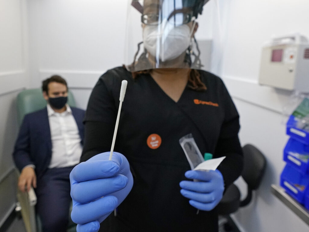 A medical assistant holds a swab after testing a man on Wednesday at the new COVID-19 testing facility at Boston Logan International Airport. (Elise Amendola/AP Photo)