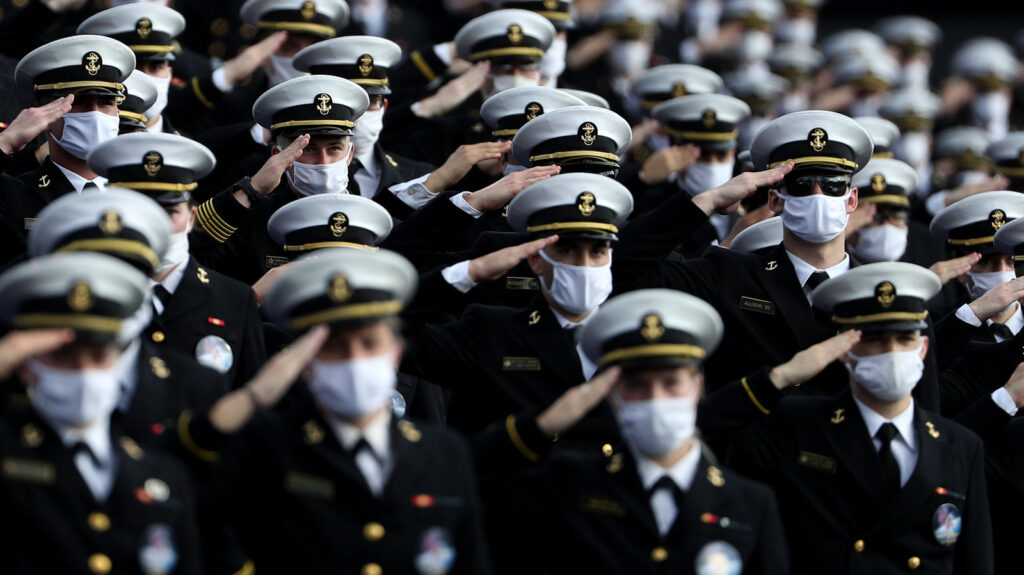 Houston v Navy Midshipmen wearing face masks stand and salute.