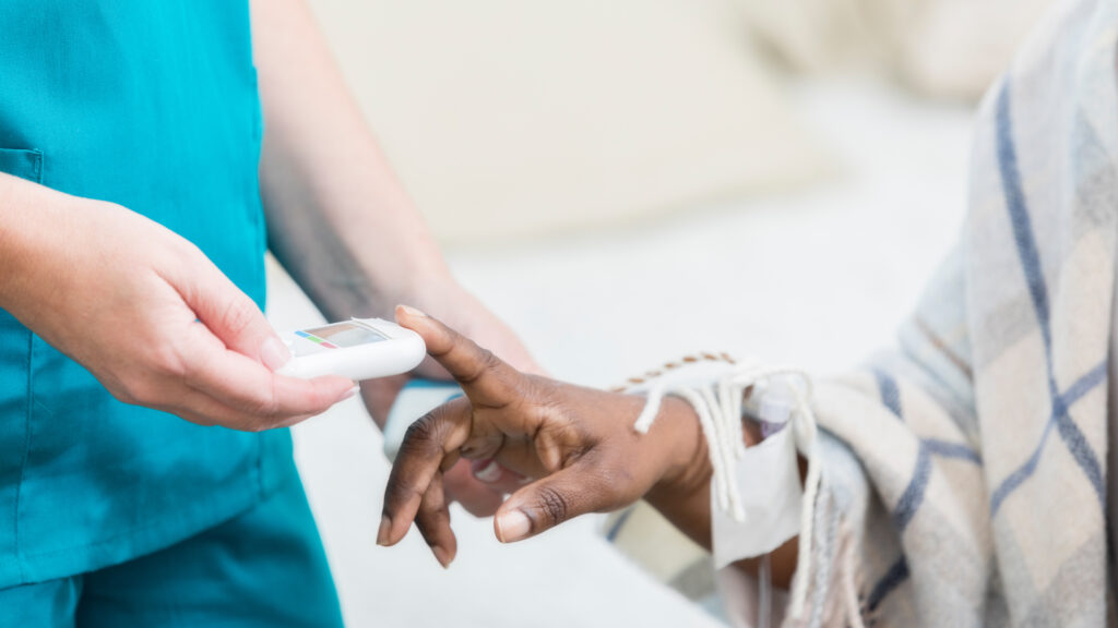 Unrecognizable woman uses a glaucometer to check a female patient’s blood sugar level. On average, each U.S. nursing home is connected to seven others through shared staff, a study by Yale and UCLA researchers suggests. Rigorous infection control measures can curb spread of the coronavirus, but many workers say they still don't have sufficient masks and other PPE. (SDI Productions/Getty Images)