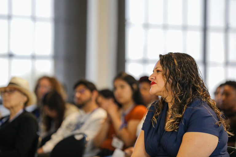 Karla Monterroso sits in the foreground of a room of people