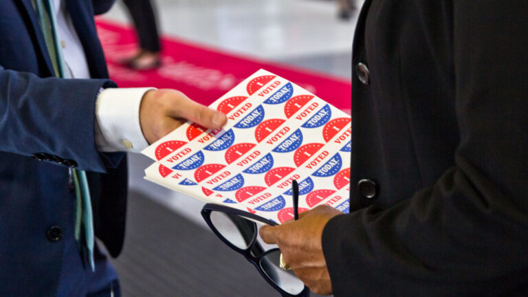 An election worker hands a sheet of 