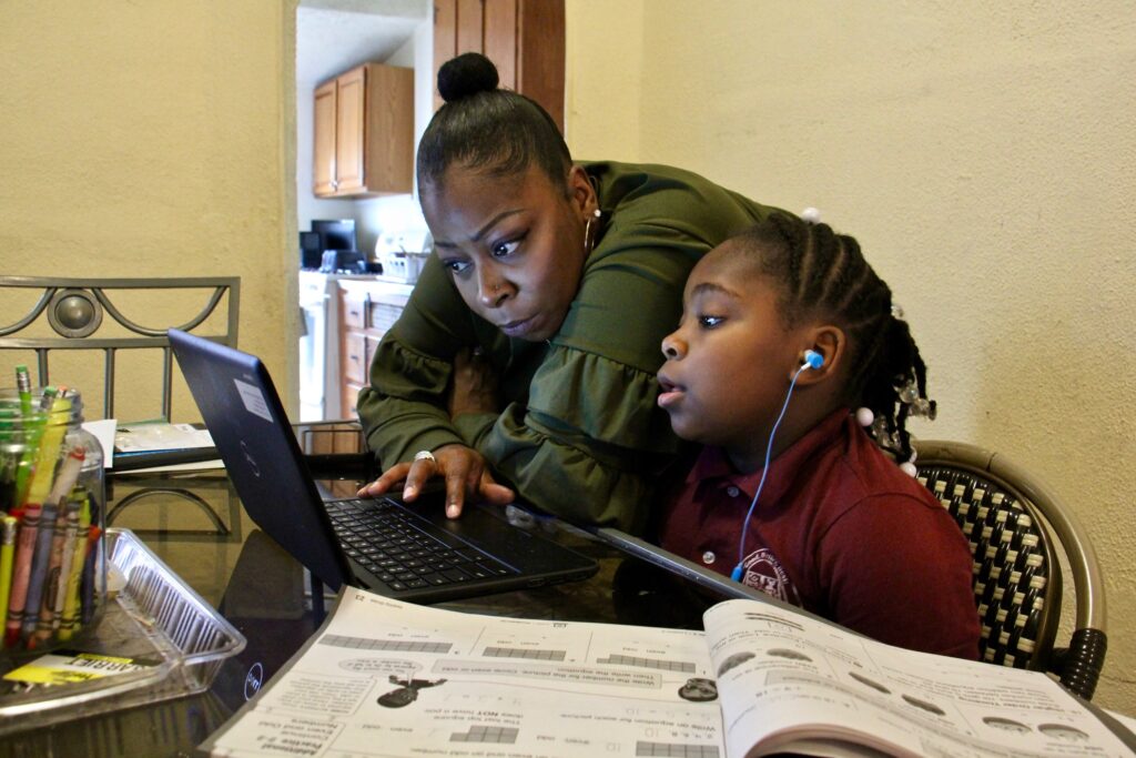 2020 10 01-e lee-yolanda biggers zyiah satterwhite-philadelphia fairhill-learning to read at virtual school 1 Yolanda Biggers helps her daughter, Zyiah Satterwhite, 7, find her assignment. After the coronavirus pandemic hit, Biggers gave up her shifts as a part-time nurse to focus all of her attention on Zyiah and her two older sisters as they adapted to virtual schooling. (Emma Lee/WHYY)