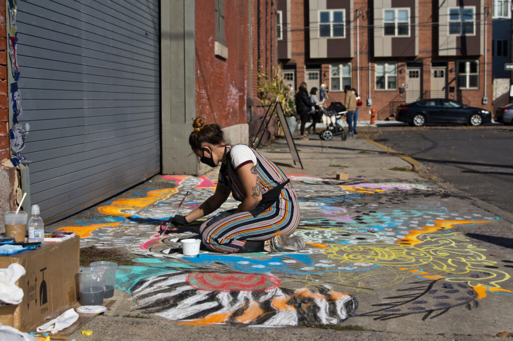 2020 11 14 k paynter philly chalk festival-6 Natalie Flor Negron creates a mural titled “Ancient Roots” for the Philadelphia Chalk Festival outside the Philadelphia Brewing Company in Kensington. (Kimberly Paynter/WHYY)