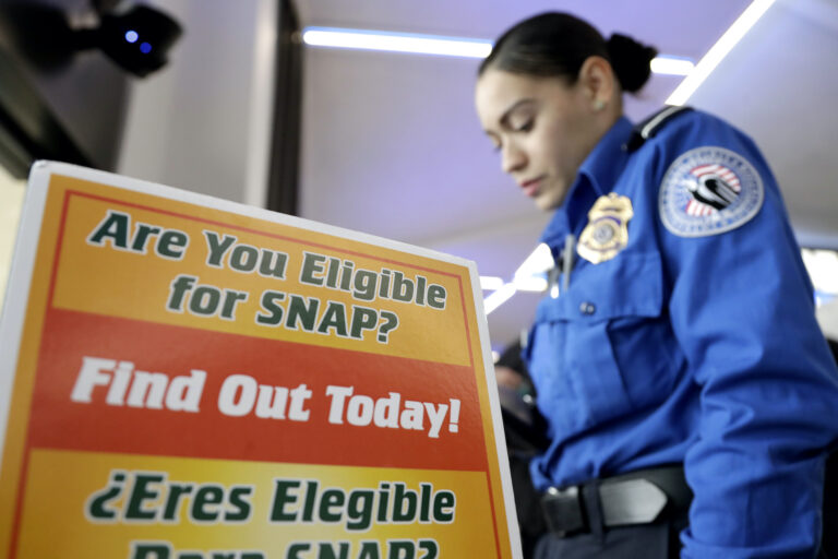 A police woman in front of a sign for SNAP eligibility