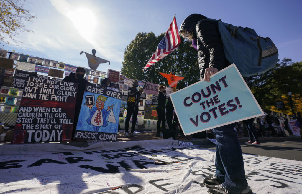 APTOPIX Election 2020 Protests Washington A demonstrator reads a banner on display at Black Lives Matter Plaza, Thursday, Nov. 5, 2020, in Washington. (AP Photo/Alex Brandon)