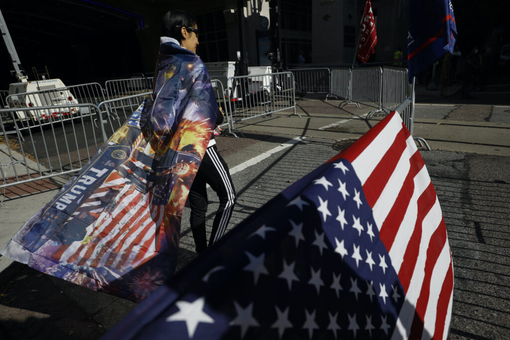 Election 2020 Protests Philadelphia A woman wears a Trump flag as a cape as supporters of President Donald Trump protest outside the Pennsylvania Convention Center, where vote counting continues, in Philadelphia, Monday, Nov. 9, 2020, two days after the 2020 election was called for Democrat Joe Biden. (AP Photo/Rebecca Blackwell)