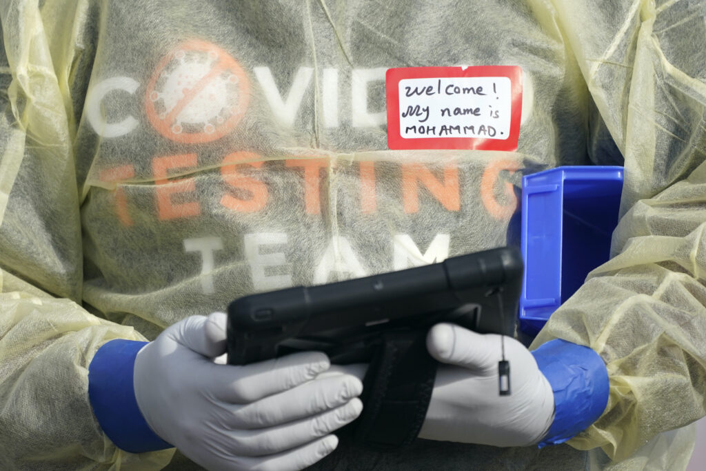 Virus Outbreak A worker wearing gloves, and other PPE holds a tablet computer as he waits to check people in, Wednesday, Oct. 28, 2020, at a King County coronavirus testing site in Auburn, Wash., south of Seattle. (AP Photo/Ted S. Warren)
