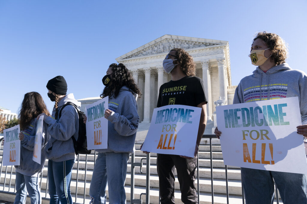 Demonstrators hold signs in front of the U.S. Supreme Court as arguments are heard about the Affordable Care Act Tuesday, Nov. 10, 2020, in Washington. (AP Photo/Alex Brandon)