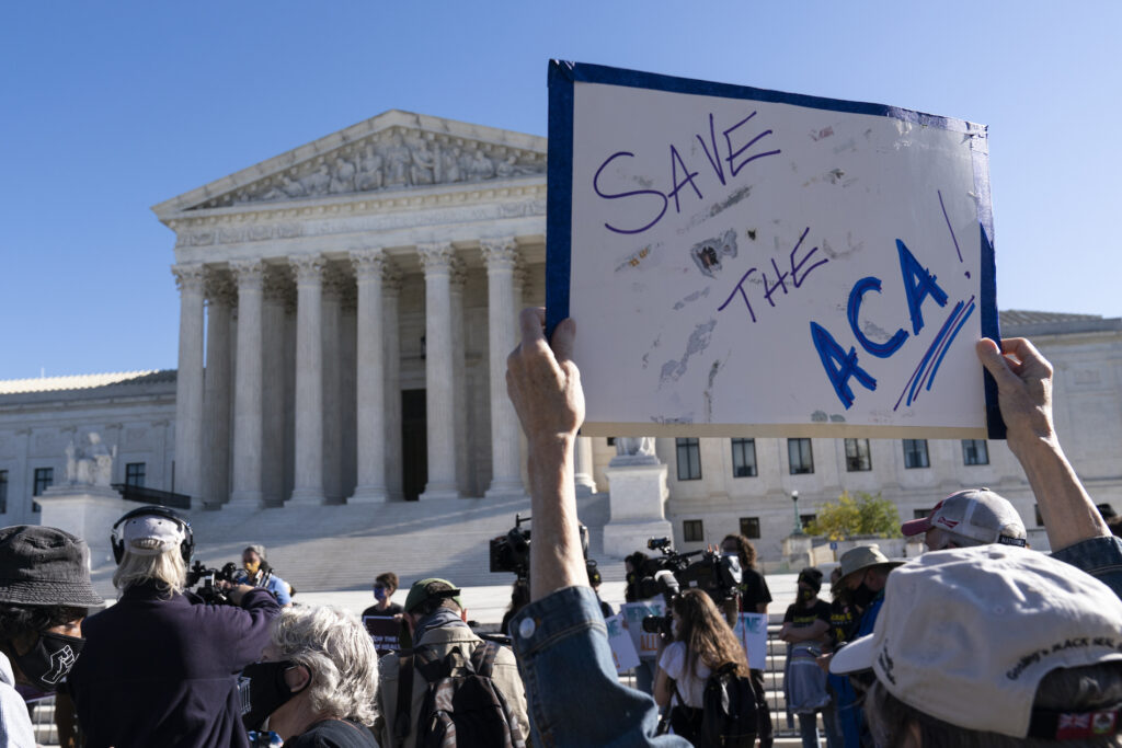 Supreme Court Health Care A demonstrator holds a sign in front of the U.S. Supreme Court as arguments are heard about the Affordable Care Act, Tuesday, Nov. 10, 2020, in Washington. (AP Photo/Alex Brandon)