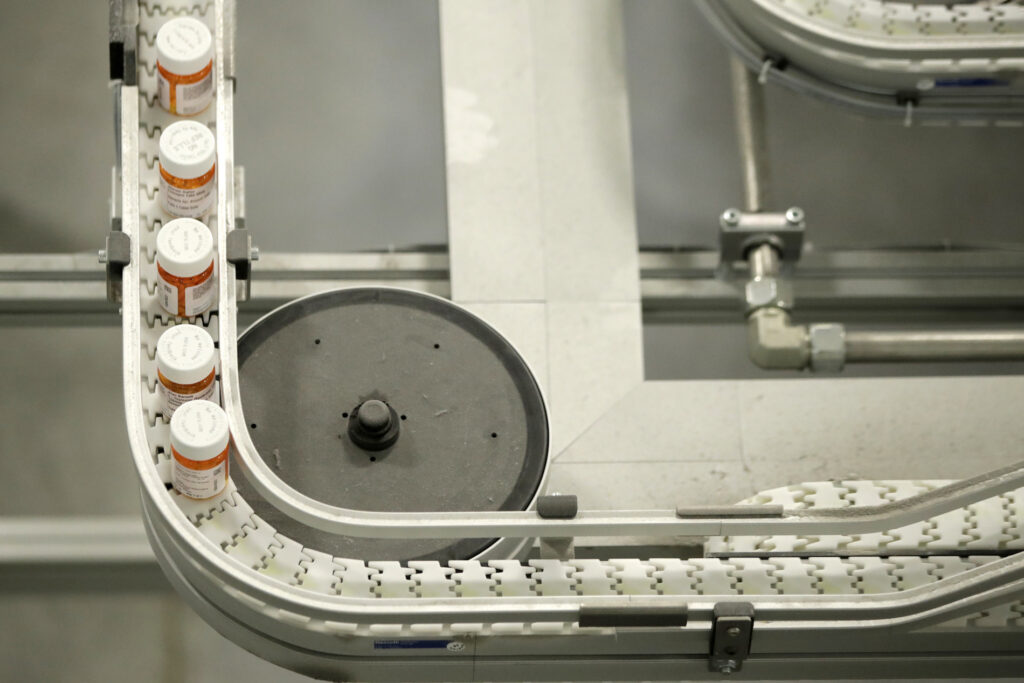 Bottles of medicine ride on a belt at the Express Scripts mail-in pharmacy warehouse, Tuesday, July 10, 2018, in Florence, N.J. (AP Photo/Julio Cortez)