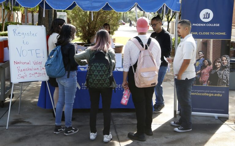 In this Sept. 24, 2019 file photo students at Phoenix College gather to fill out voter registration forms on National Voter Registration Day on campus, in Phoenix. (AP Photo/Ross D. Franklin)