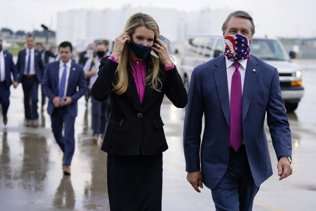 Donald Trump FILE- In this July 15, 2020, file photo Sen. Kelly Loeffler, R-Ga., puts on a face mask as she walks with Sen. David Perdue, R-Ga., right, at UPS Hapeville Airport Hub in Atlanta. (AP Photo/Evan Vucci, File)