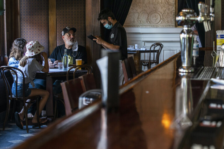 A waiter takes the order of customers inside a restaurant