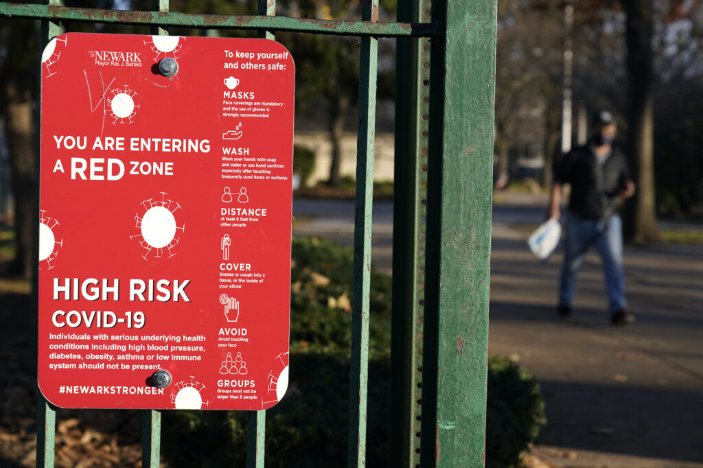 Virus Outbreak New Jersey A sign at the entrance to a park warns pedestrians about increased risk for the coronavirus in the Ironbound section of Newark