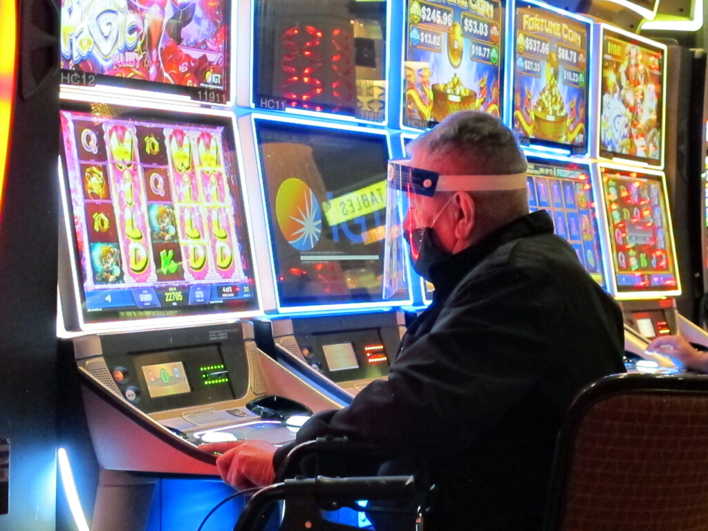 A man wears a face shield while playing a slot machine at the Golden Nugget casino