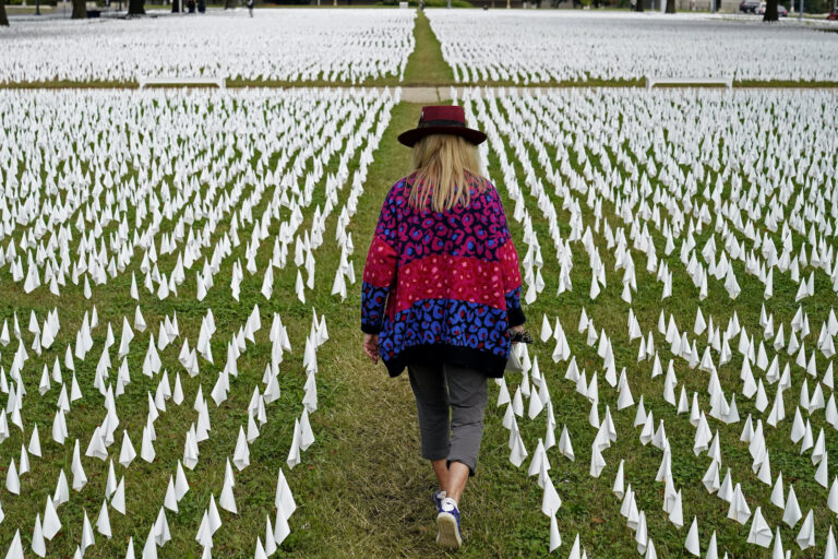 Artist Suzanne Brennan Firstenberg walks among thousands of white flags planted in remembrance of Americans who have died of COVID-19