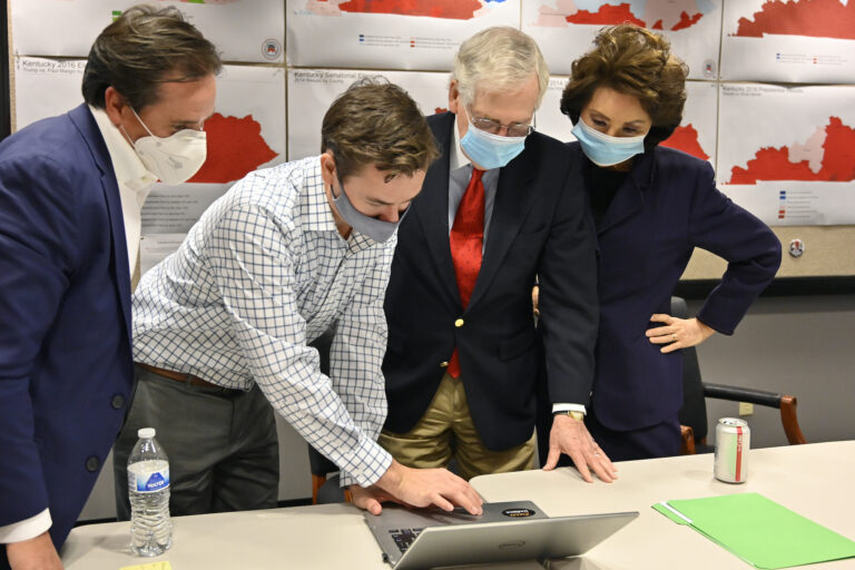 Republican Senate candidate Sen. Mitch McConnell, center, and his wife, Secretary of Transportation Elaine Chao, right, look on as aides show him the election results
