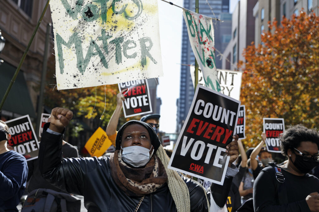 Zhanon Morales, 30, of Philadelphia, raises her fist as demonstrators call for all votes be counted outside the Pennsylvania Convention Center