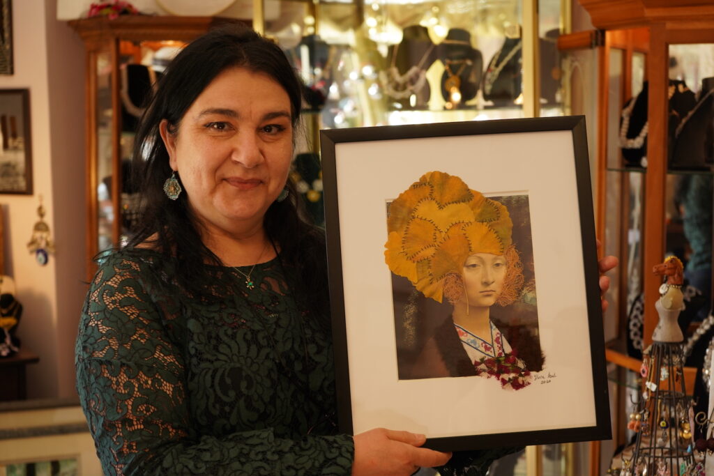 DSC05656 Ylvia Asal holding up a piece of her artwork in her Anatolia Art & Craft Studio. (Kenny Cooper/WHYY)