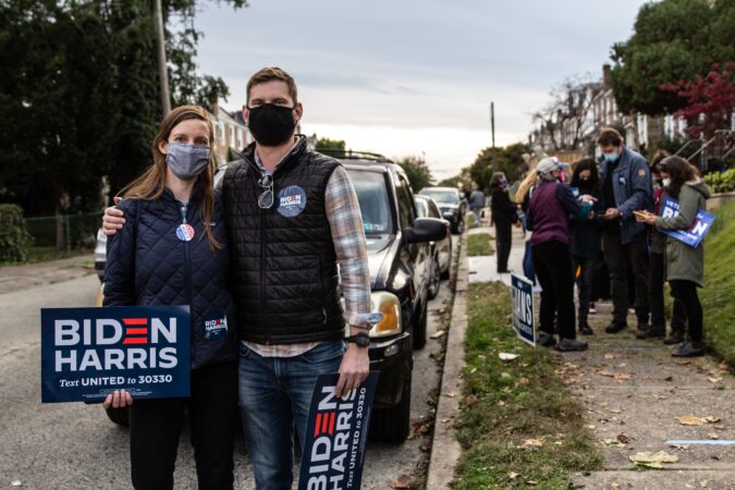 Laurel Peterson (left) and Jason Hartwig hold a Biden-Harris sign
