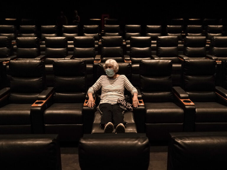 A woman sits in a theater in Irvine, Calif., waiting for a movie to start, on Sept. 8. A COVID-19 vaccine could unleash pent-up spending from households that have mostly avoided activities like going to the gym during the coronavirus pandemic. (Jae C. Hong/AP Photo)