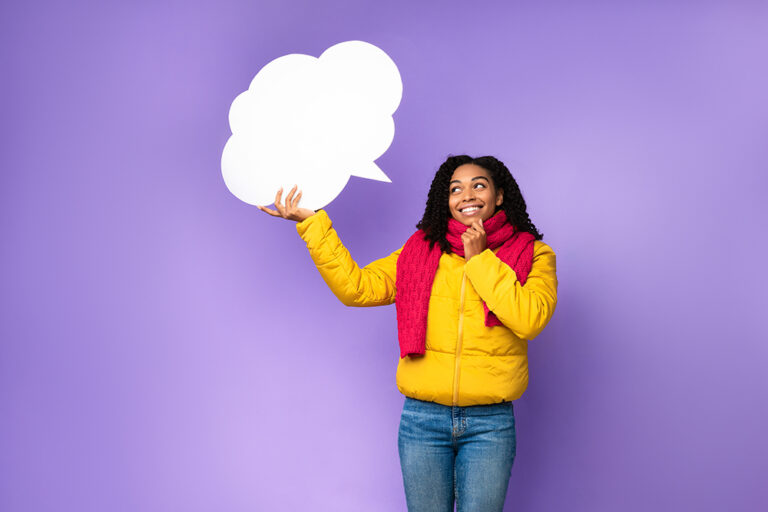 A cheerful Black woman holding an empty speech bubble above her head