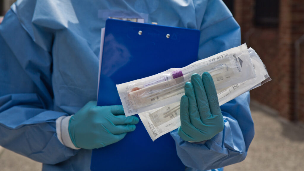 Dr. Ala Stanford, a pediatric surgeon, holds COVID-19 testing materials outside the mobile testing site of the Black Doctors COVID-19 Consortium. (Kimberly Paynter/WHYY)