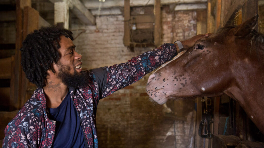 Jamil Prattis pets his favorite horse, 100, at the Fletcher Street Stables.