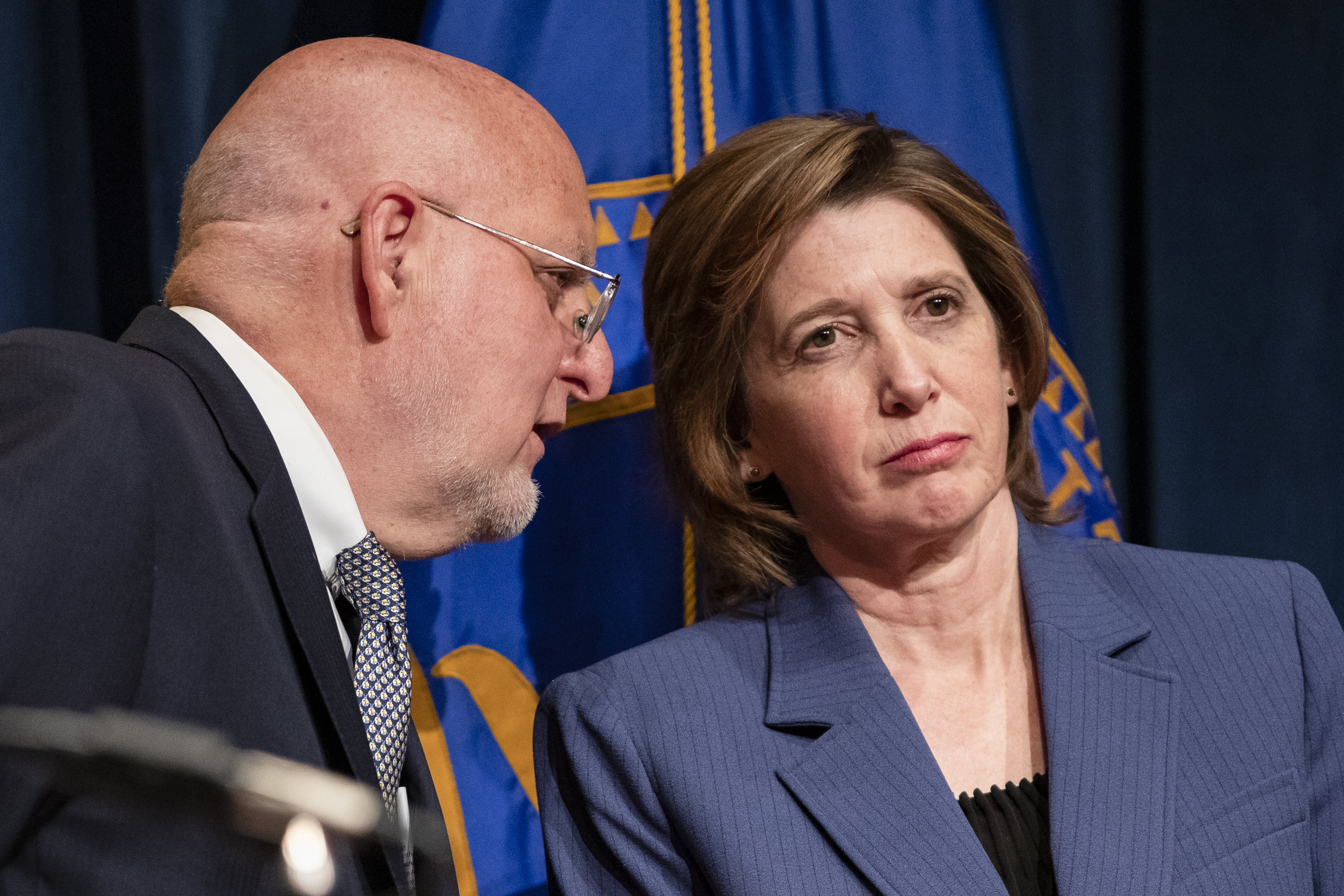 Centers for Disease Control and Prevention Director Robert Redfield whispers to National Center for Immunization and Respiratory Diseases Director Nancy Messonnier during a press conference 
