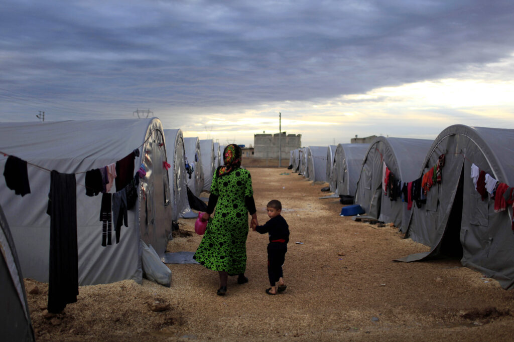 A Kurdish refugee mother and son from the Syrian town of Kobani walk beside their tent in a camp in the southeastern town of Suruc on the Turkish-Syrian border in 2014 in Sanliurfa, Turkey. President-elect Joe Biden aims to reverse the Trump administration’s dramatic cuts to refugee admissions. A Kurdish refugee mother and son from the Syrian town of Kobani walk beside their tent in a camp in the southeastern town of Suruc on the Turkish-Syrian border in 2014 in Sanliurfa, Turkey. President-elect Joe Biden aims to reverse the Trump administration's dramatic cuts to refugee admissions. (Gokhan Sahin/Getty Images)