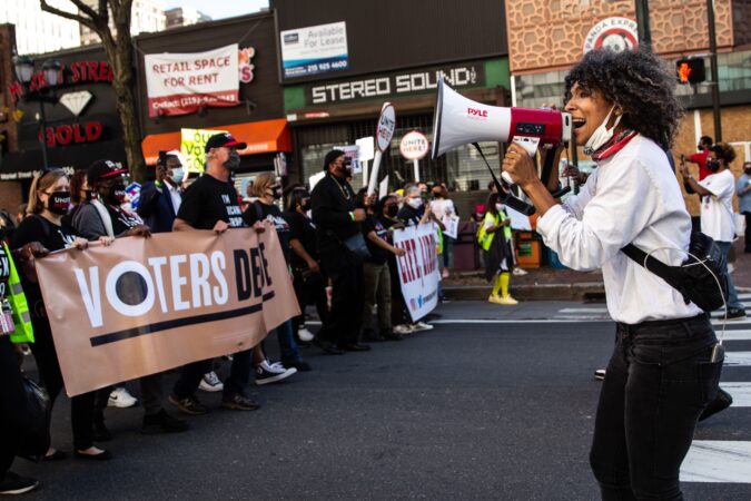 Sam Pride of Girls Rock Philly leads a song as demonstrators celebrate