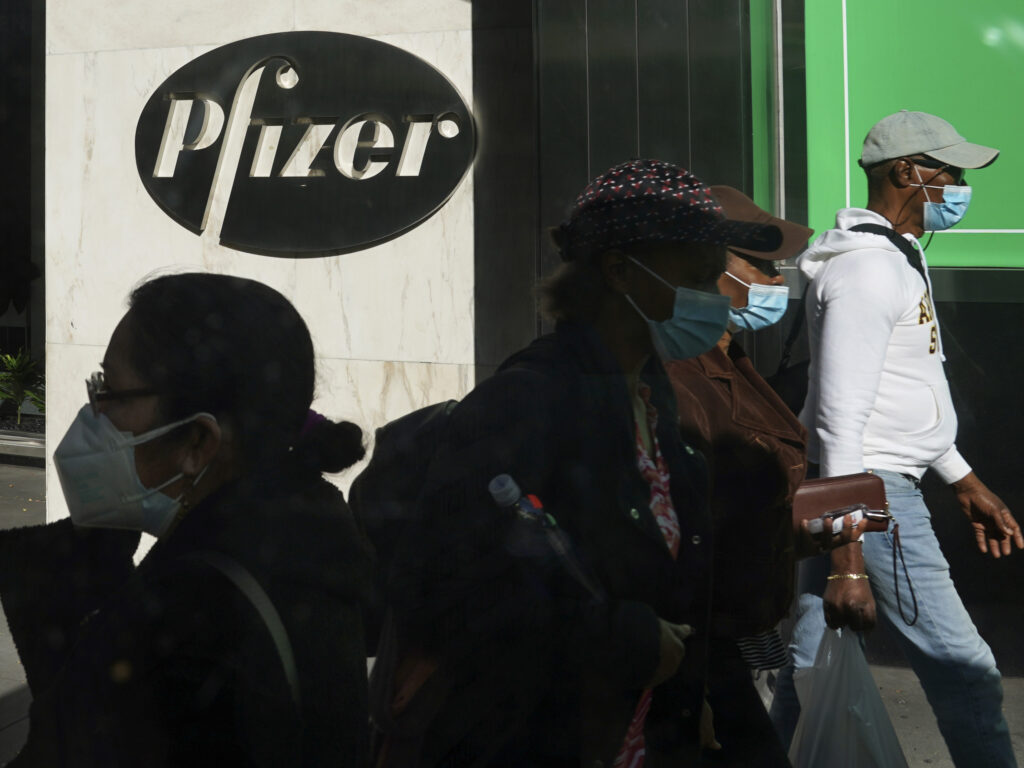 Pfizer plans to file within days with the Food and Drug Administration to allow emergency use of its COVID-19 vaccine. Pedestrians walk past Pfizer world headquarters