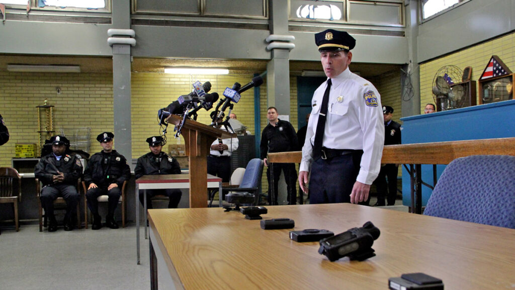Lt. Tom McLean displays the array body camera models the police department tested when the the program began in 2014. (Emma Lee/WHYY, file)