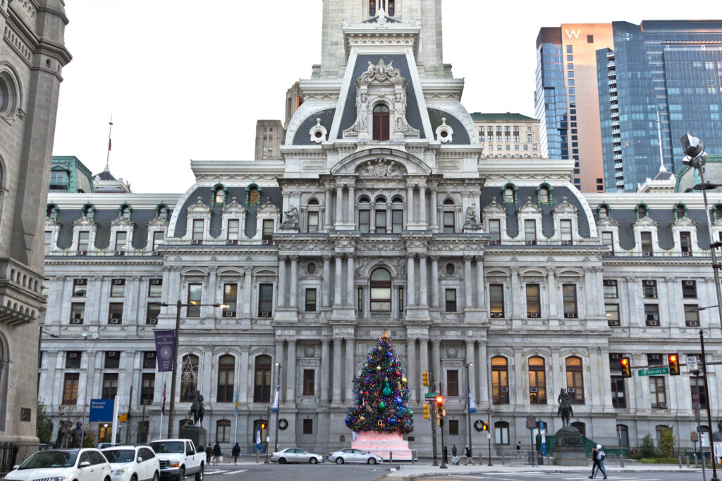 A Christmas tree is visible in front of Philadelphia City Hall.