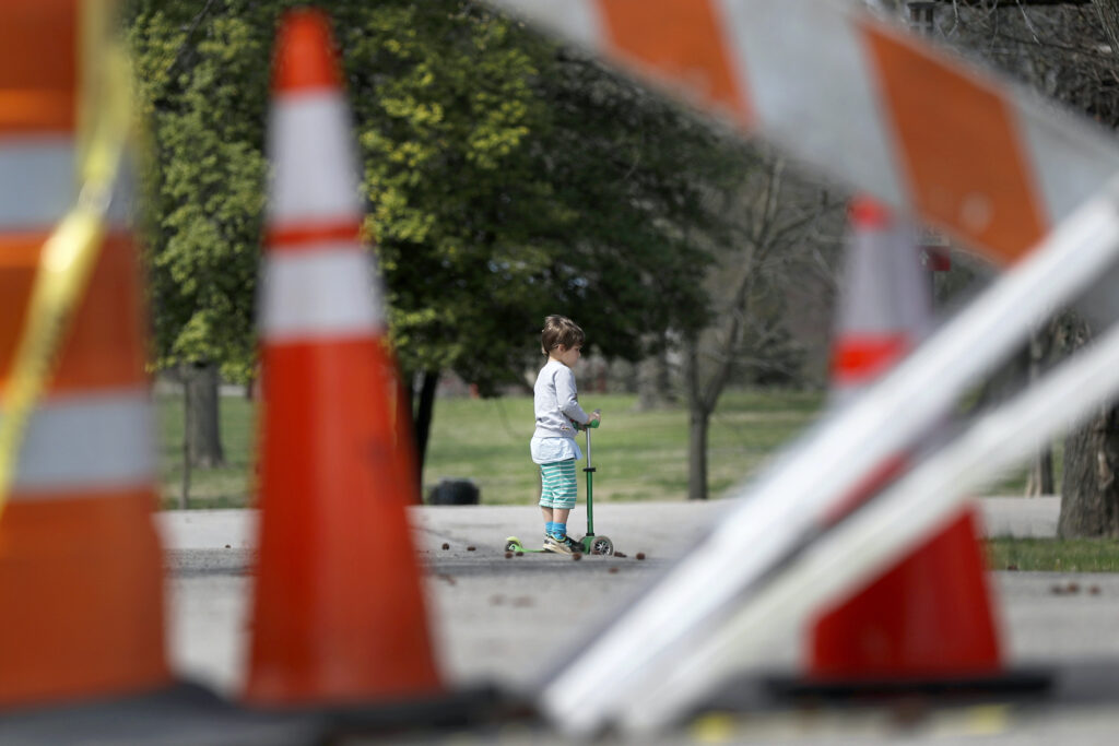Virus Outbreak Child Abuse Hotlines In this March 31, 2020 file photo, a child rides a scooter past barricades at an entrance to Tower Grove Park in St. Louis. (AP Photo/Jeff Roberson)