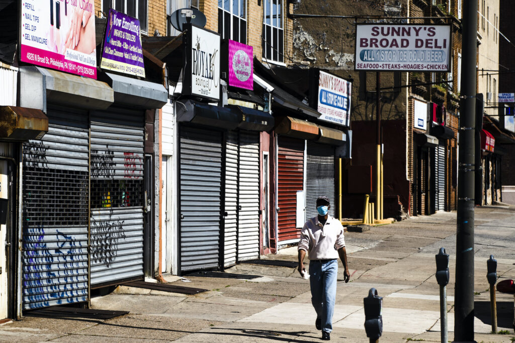 APTOPIX Virus Outbreak Pennsylvania Unemployment A person wearing a protective face mask as a precaution against the coronavirus walks past stuttered businesses in Philadelphia, Thursday, May 7, 2020. (AP Photo/Matt Rourke)