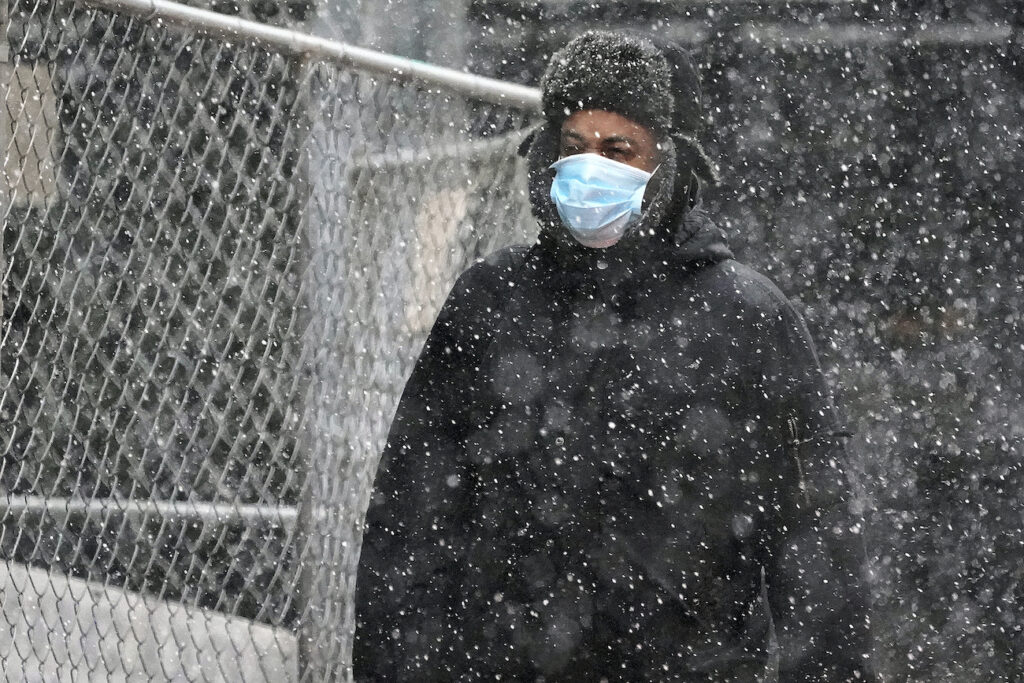 Virus Outbreak Pennsylvania A man wearing a mask walks through a mid-afternoon snow squall in downtown Pittsburgh on Tuesday, Nov. 17, 2020. (AP Photo/Gene J. Puskar)