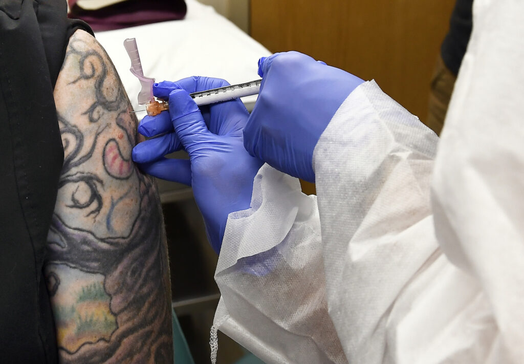 Virus Outbreak In this July 27, 2020, file photo, Nurse Kathe Olmstead, right, gives volunteer Melissa Harting, of Harpersville, N.Y., an injection as a study of a possible COVID-19 vaccine, developed by the National Institutes of Health and Moderna Inc., gets underway in Binghamton, N.Y. (AP Photo/Hans Pennink)