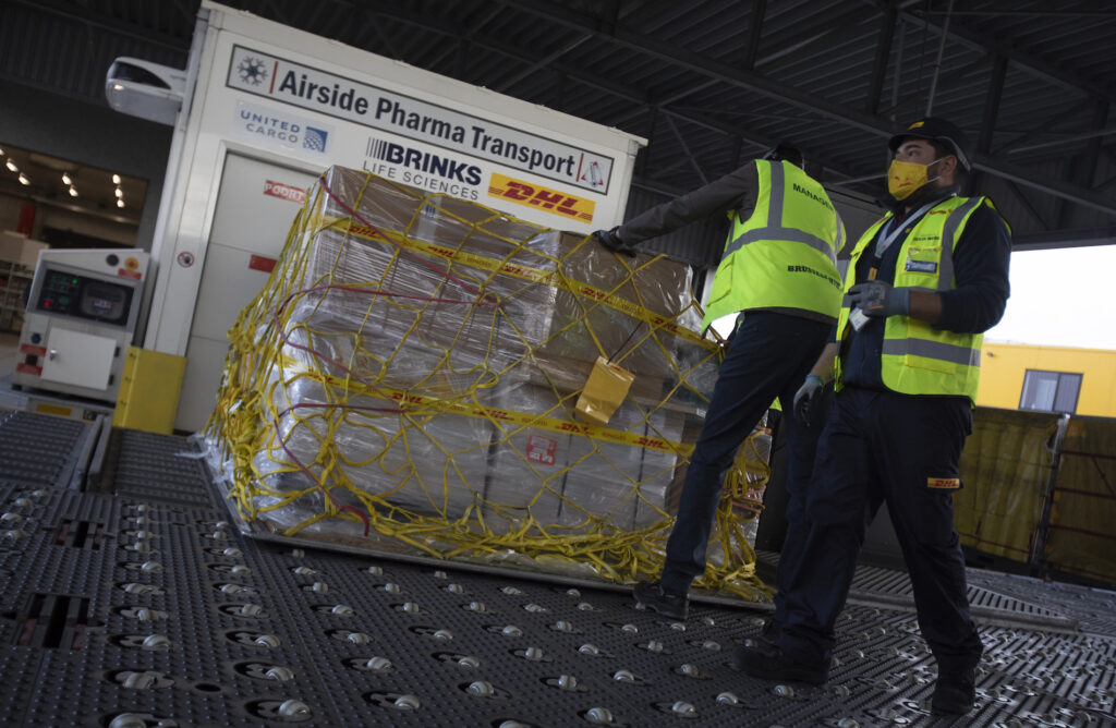 Virus Outbreak Belgium Vaccines Cargo workers move a palette of cool boxes and other items into a pharma transport container during a demonstration on the handling and logistics of vaccines and medicines at the DHL cargo warehouse in Steenokkerzeel, Belgium, Tuesday, Dec. 1, 2020. (AP Photo/Virginia Mayo)