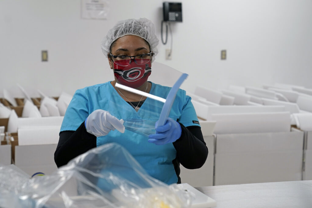 NC Virus Outbreak Cooper Visit Gilero employee Anne-Marie Dutch assembles a face shield in Pittsboro, N.C., as Gov. Roy Cooper tours the facility Thursday, Dec. 3, 2020. The medical device manufacturer began producing face shields when the pandemic started and also produces swabs for rapid tests in addition to self contained oxygenated negative pressure environments. (AP Photo/Gerry Broome)