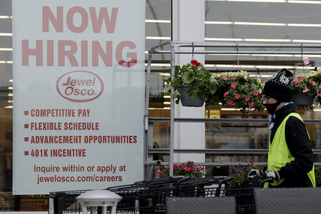 Virus Outbreak A man pushes carts as a hiring sign shows at a Jewel Osco grocery store in Deerfield, Ill., Thursday, April 23, 2020. (AP Photo/Nam Y. Huh)