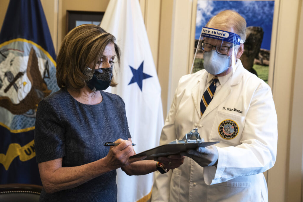 Virus Outbreak Congress Vaccines Speaker of the House Nancy Pelosi, D-Calif., signs a form next to Dr. Brian Monahan, attending physician Congress of the United States after she received a Pfizer-BioNTech COVID-19 vaccine shot in Washington, Friday, Dec. 18, 2020. (Anna Moneymaker/The New York Times via AP, Pool)